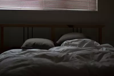 rumpled bed in a dark and cozy bedroom