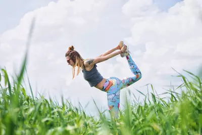 woman with colorful exercise pants stretching outside in the grass